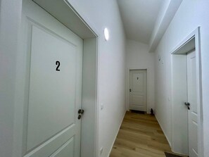 A hallway with white doors numbered 2 and 3, wooden flooring, and a white ceiling with a light fixture. - Apartment 'Nr. 4' with Wi-Fi (Jettingen-Scheppach)