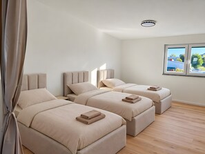 Une chambre d’hôtel avec deux lits, une fenêtre et un luminaire au plafond.