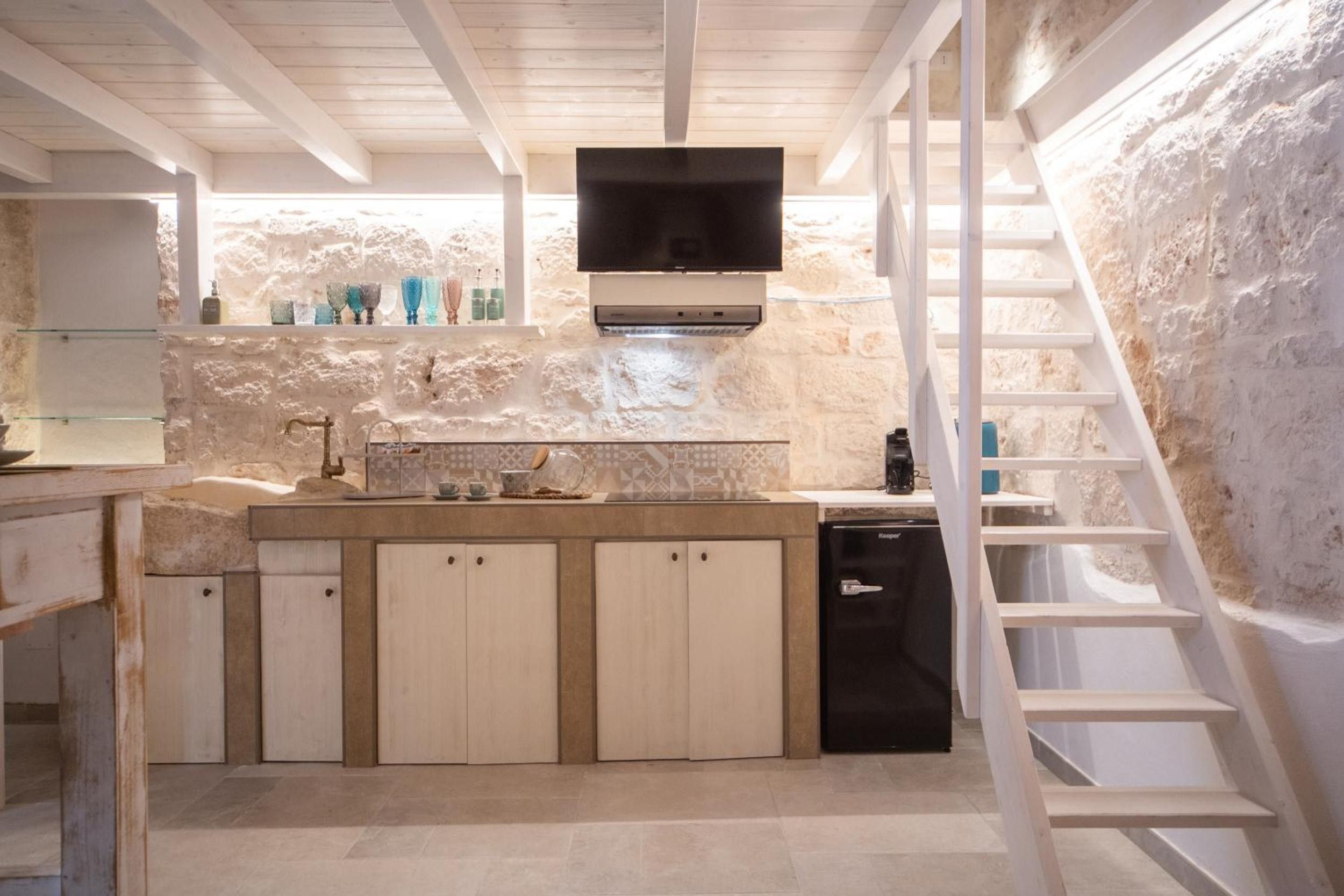 A compact kitchen with a built-in dishwasher, a wooden counter, and a TV mounted above the stove.
