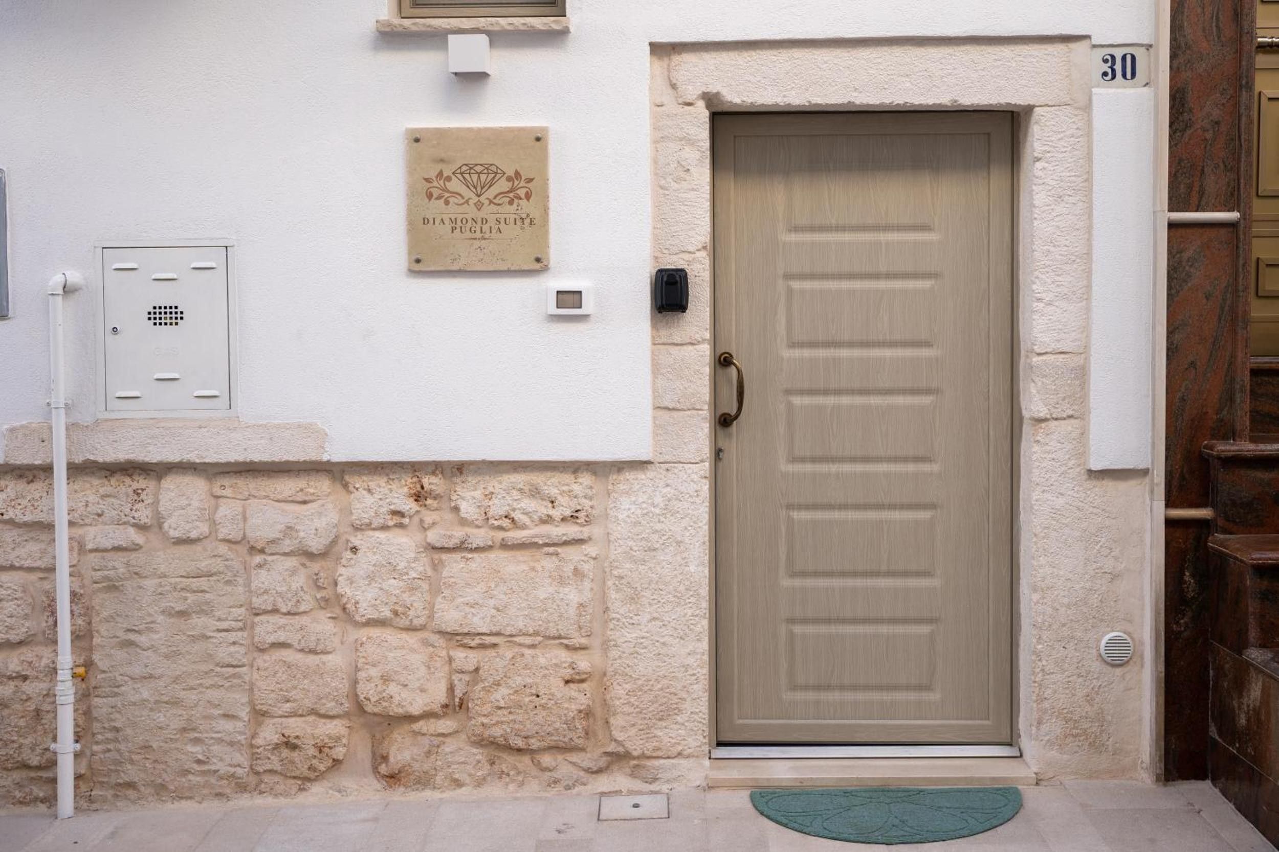 L'ingresso di un edificio con un muro in pietra, una porta con il numero e una targa.