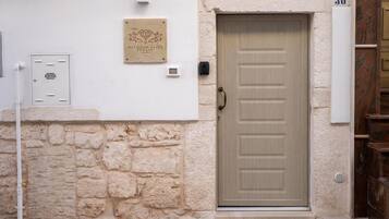 L'ingresso di un edificio con un muro in pietra, una porta con il numero e una targa.