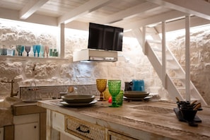 Una cocina con pared de piedra, techo de madera y televisor sobre la encimera.