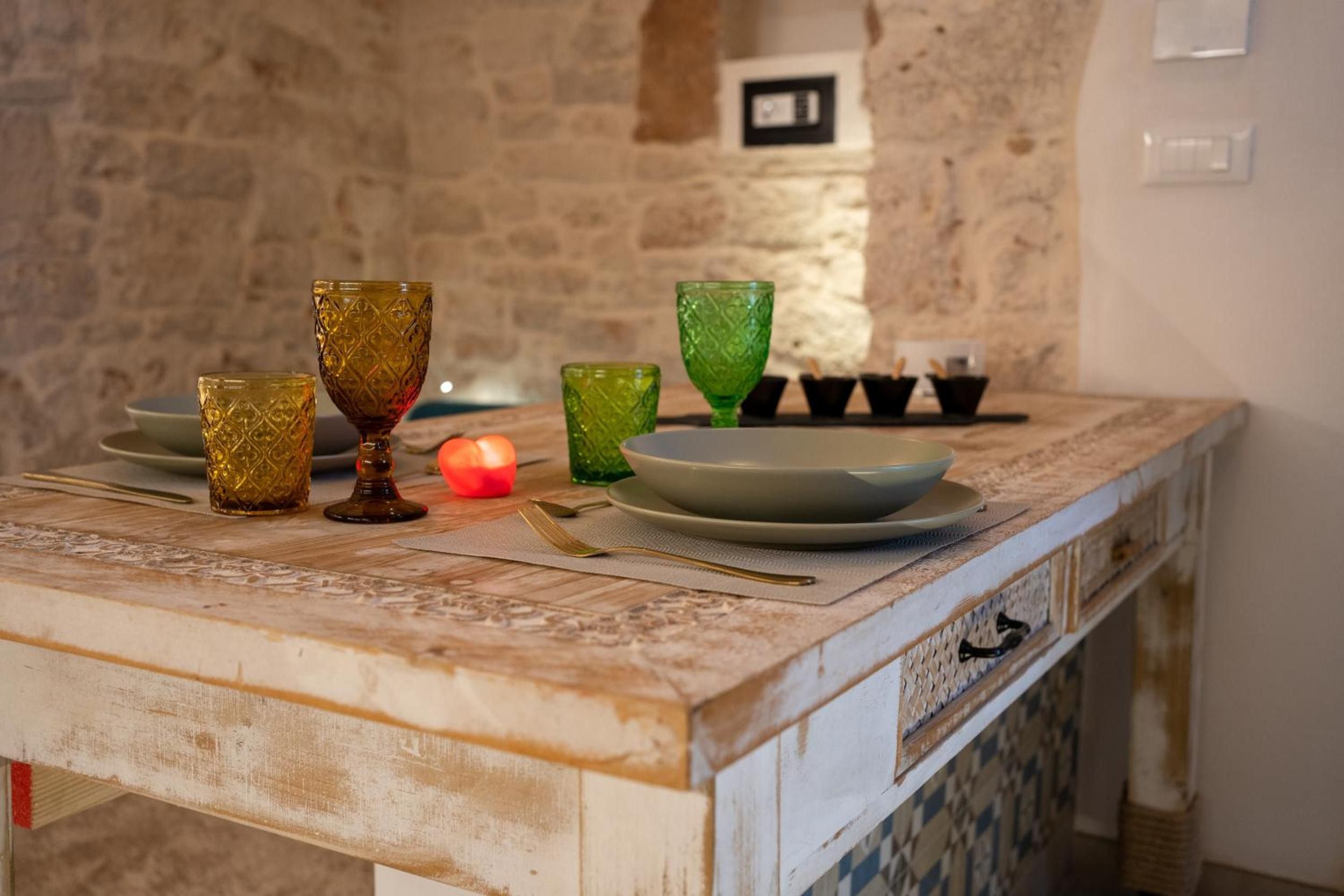 A kitchen counter with a stone wall, a candle, and various glassware.