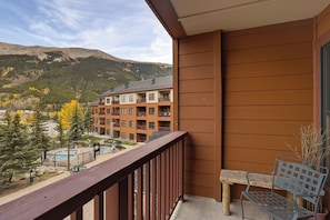 A balcony with a view of a multi-story building and mountains in the background. - Copper Springs Getaway with Great Ski Access (Copper Mountain)