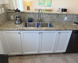 A kitchen with granite countertops, a stainless steel sink, white cabinetry, and a coffee maker. - "Beach, Please!" Ocean View Townhome.  Three bed, three bath.  Sleeps 10. (Bimini Bay)