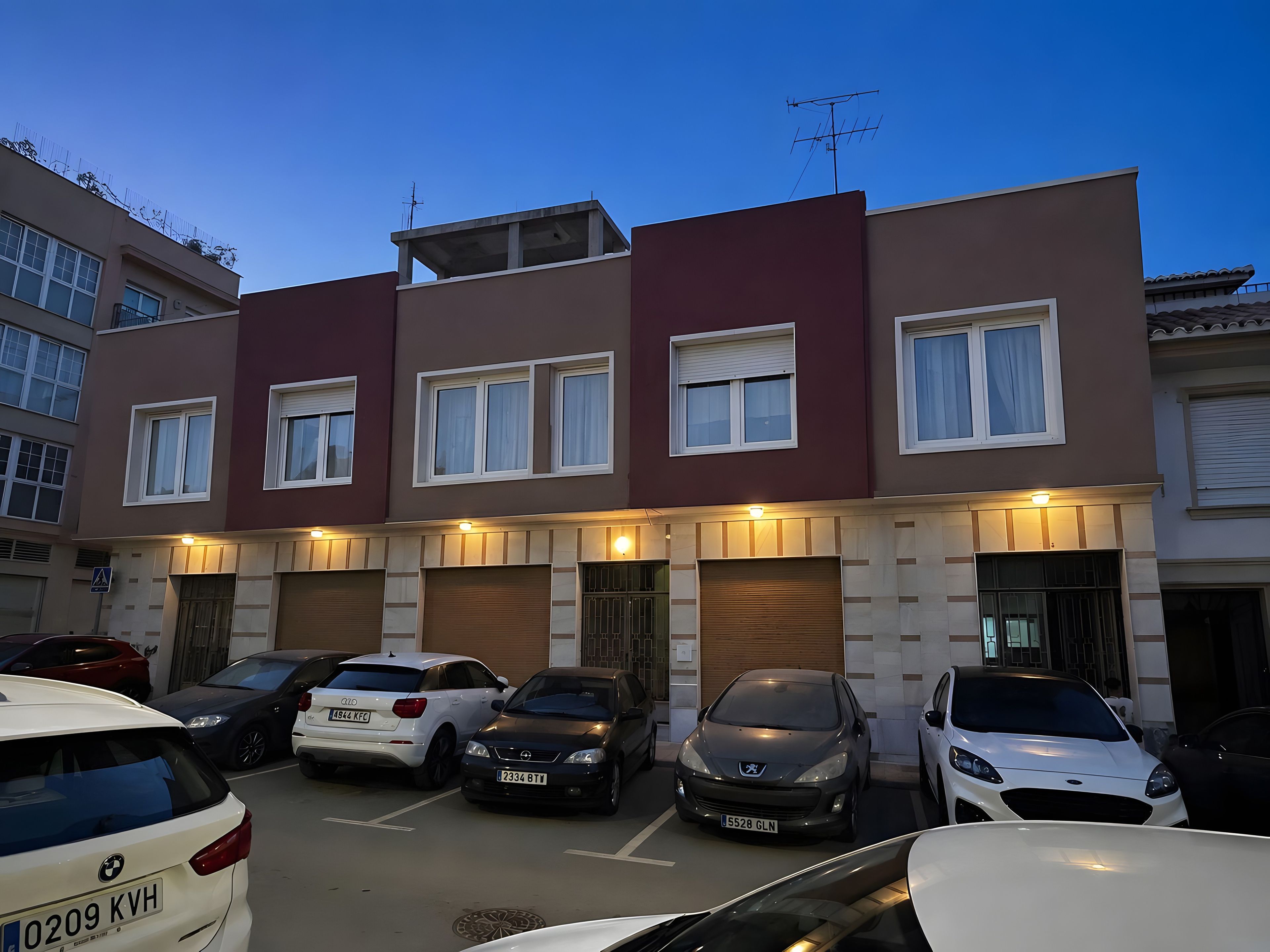 Un edificio residencial de varios pisos con un área de estacionamiento al frente.