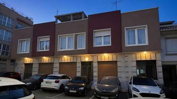 Un edificio residencial de varios pisos con un área de estacionamiento al frente.
