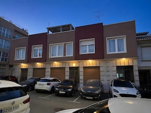 Een meerlaags woongebouw met een parkeerplaats ervoor.