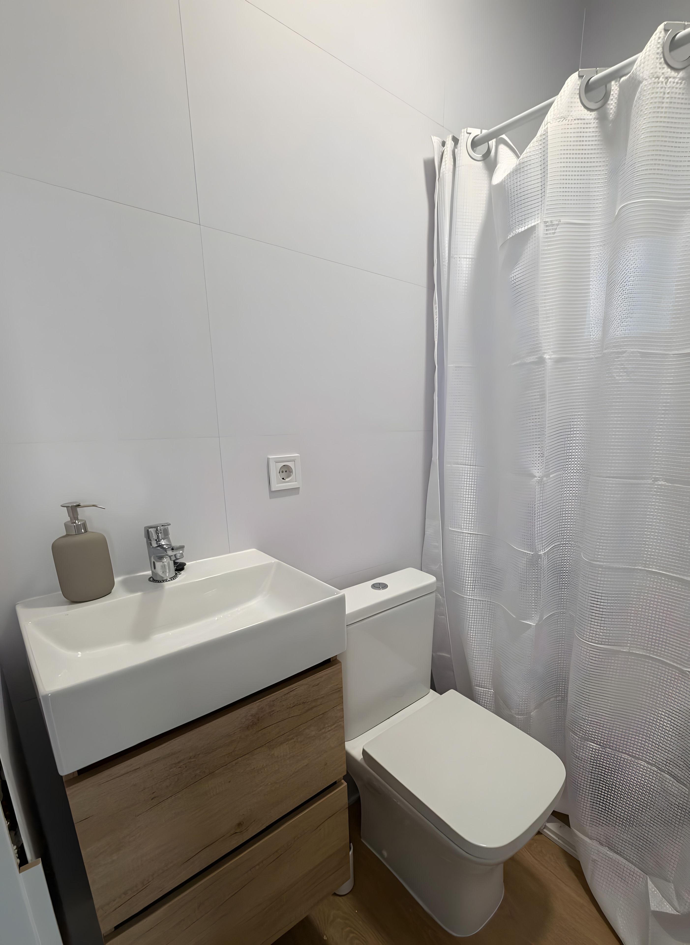 Un baño con lavamanos blanco, inodoro y cortina de ducha.