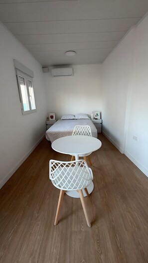 Een slaapkamer met een bed, nachtkastjes, een ronde tafel met stoelen en een plafond met ingebouwde verlichting.