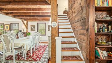 A dining area with a table and chairs, a staircase with a wooden railing, and a bookshelf with books and decorative items.