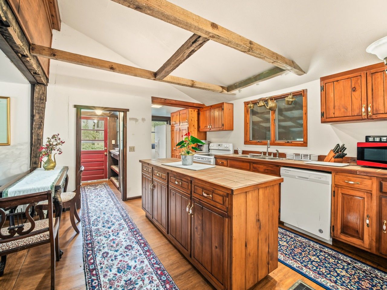 A kitchen with wooden cabinets, a central island, and a red door.
