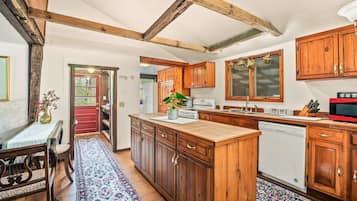 A kitchen with wooden cabinets, a central island, and a red door.