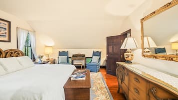 Ett hotellrum med en stor säng, två stolar, en byrå och en spegel.