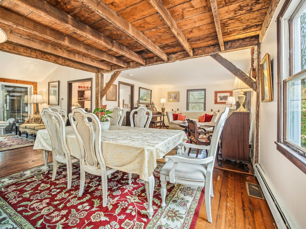 A dining area with a wooden ceiling, a table with chairs, and a patterned rug.