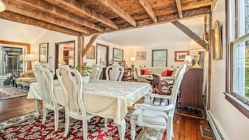 A dining area with a wooden ceiling, a table with chairs, and a patterned rug.