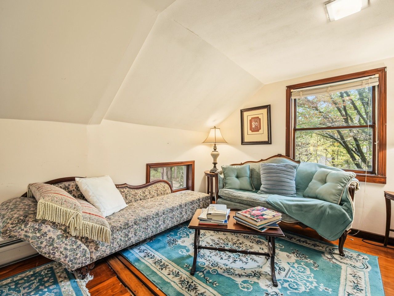 A cozy living room with two sofas, a coffee table, and a window with a view of trees.