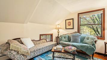 A cozy living room with two sofas, a coffee table, and a window with a view of trees.