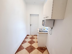 A small kitchen with a white door, a sink, and a microwave. - Put Down Roots in Vienna 1BR (Wien)