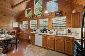 Un interno in legno con una cucina dotata di lavastoviglie, microonde e piano cottura.