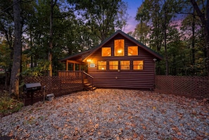 A wooden cabin with a porch, surrounded by trees and a gravel driveway. - Hot Tub-Fireplace-Private-Honeymoon-Hiking-Relax (Sevierville)