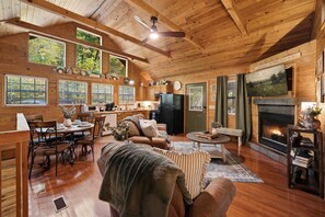 A cozy cabin interior with a dining area, kitchen, living room, and fireplace. - Hot Tub-Fireplace-Private-Honeymoon-Hiking-Relax (Sevierville)