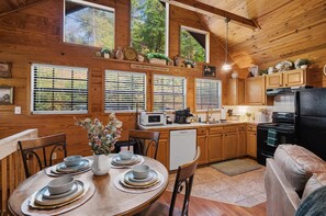 A wooden cabin interior with a kitchen, dining area, and a cozy seating space. - Hot Tub-Fireplace-Private-Honeymoon-Hiking-Relax (Sevierville)