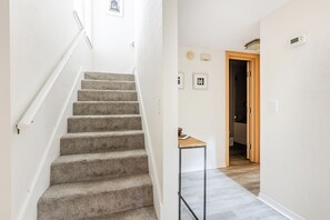 A staircase leading to a second floor with a small table and a door at the end. - Gator Glam (Gainesville)
