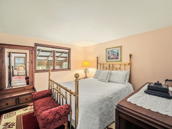 A bedroom with a bed, a nightstand, a lamp, a chair, and a dresser.