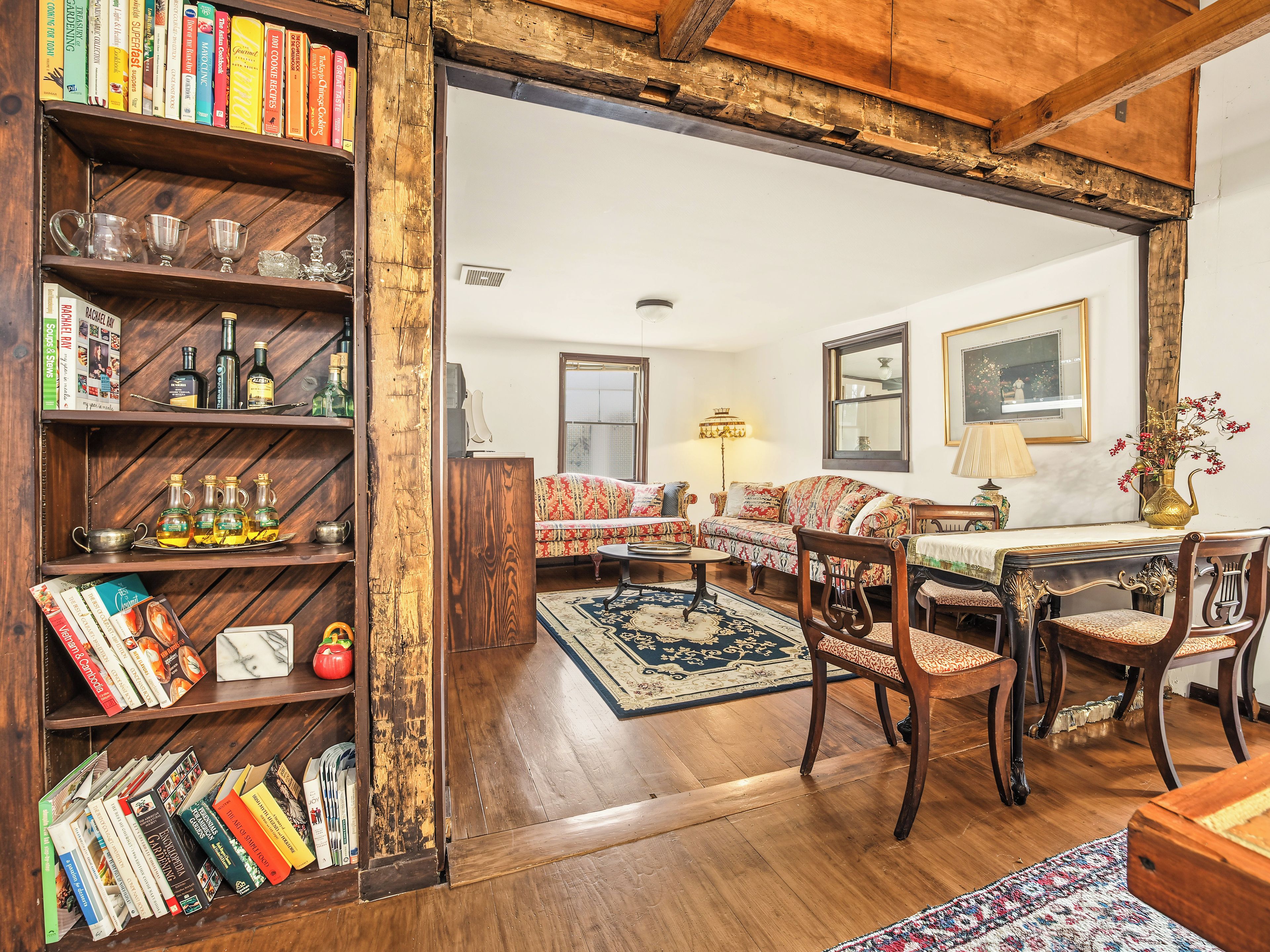 Un accogliente soggiorno con una libreria in legno, un divano decorato e un tavolo da pranzo con sedie.