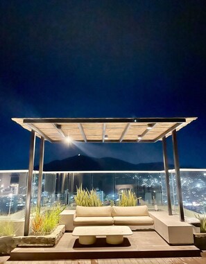An outdoor seating area with a pergola, a sofa, and planters. - Reserva del Mar (Santa Marta)