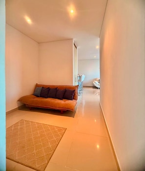 A narrow hallway with a sofa and a rug, leading to a room with a bed. - Reserva del Mar (Santa Marta)