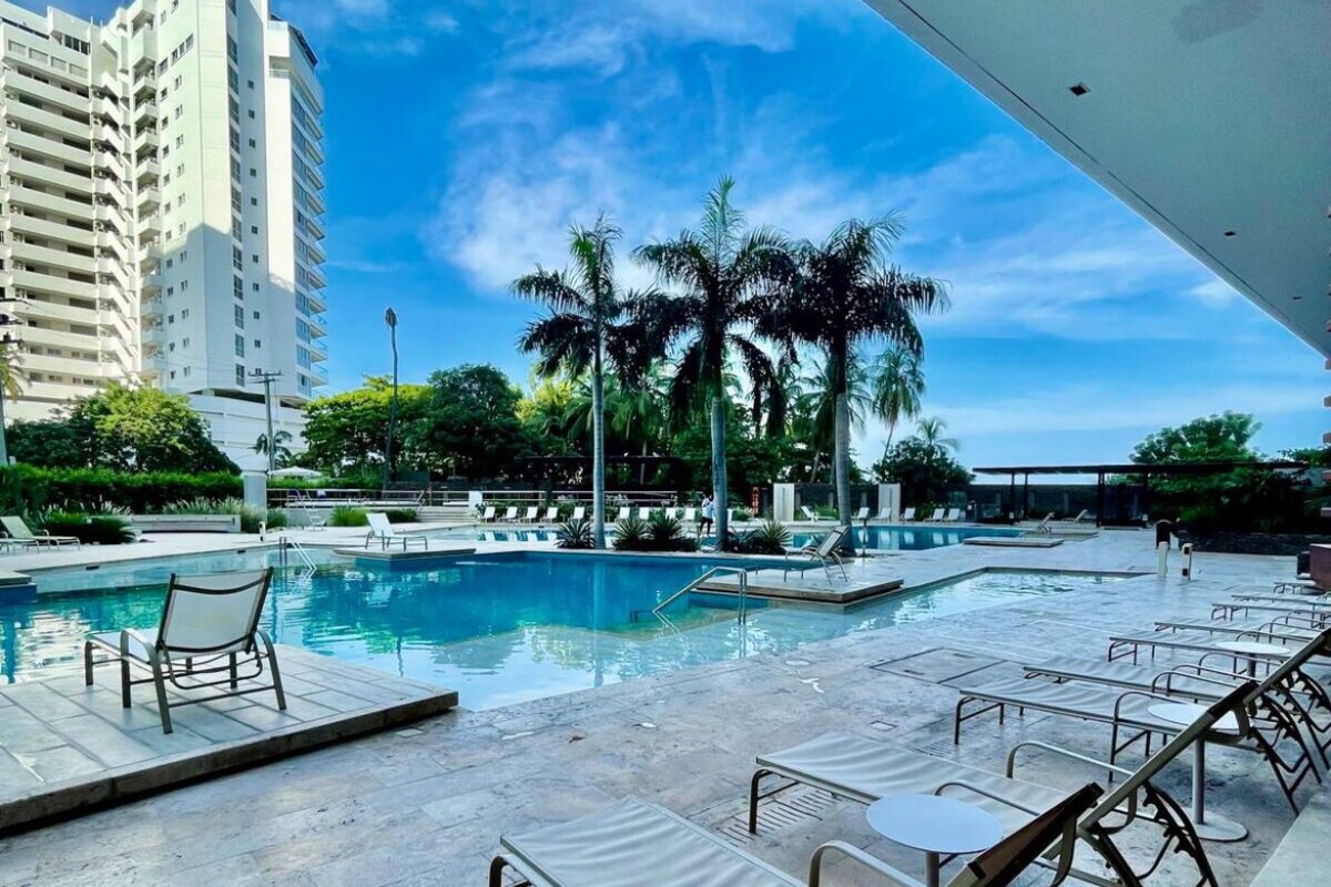 A pool area with lounge chairs and a view of a tall building.