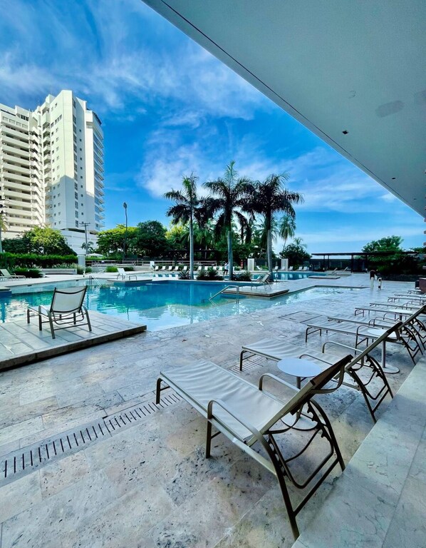 A pool area with lounge chairs and a view of a tall building. - Reserva del Mar (Santa Marta)