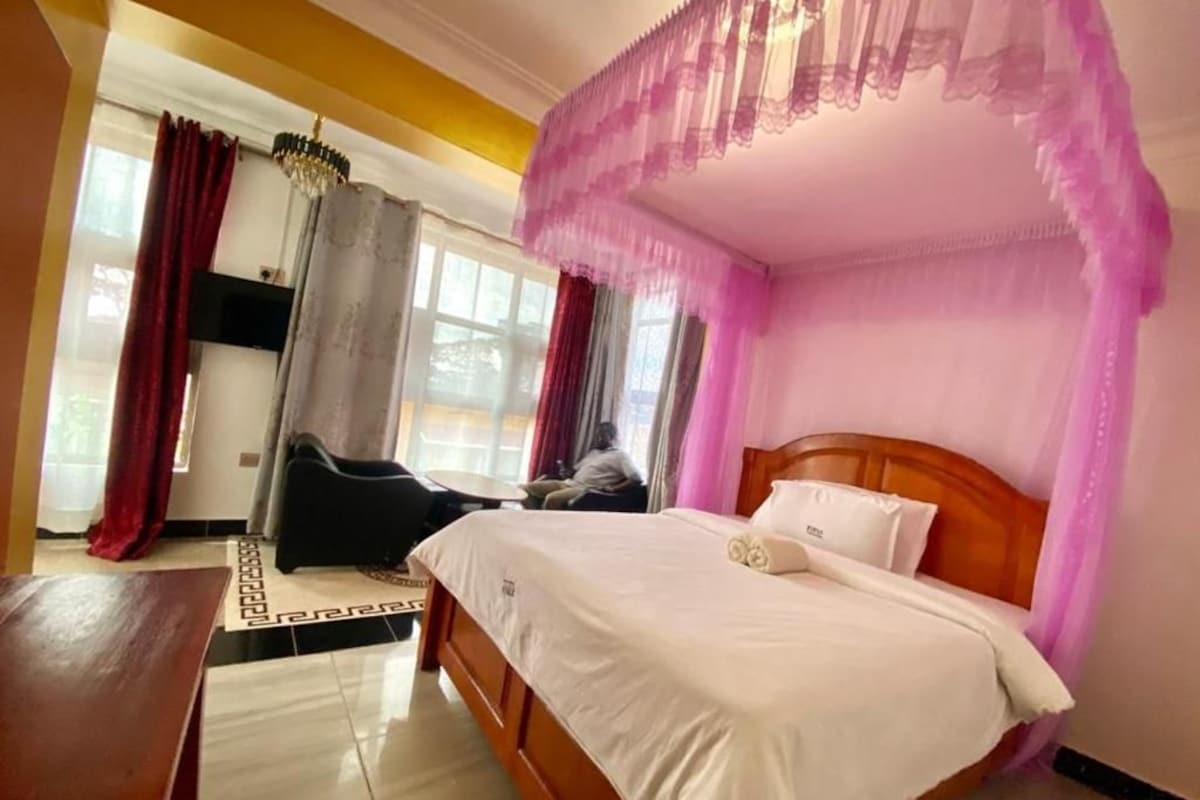Una habitación con una cama, cabecera de madera, una mesa y una silla.