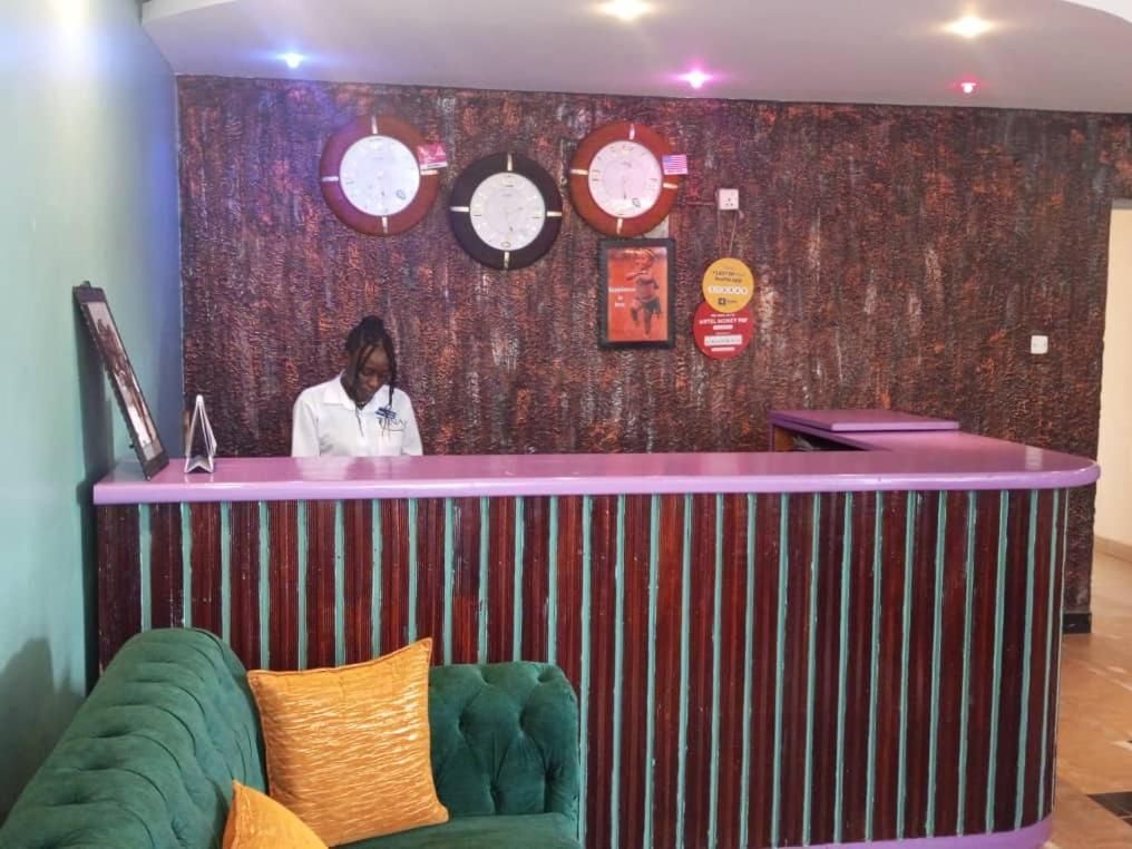 Un comptoir d’accueil avec une horloge, un tableau encadré et une affiche accrochée au mur.