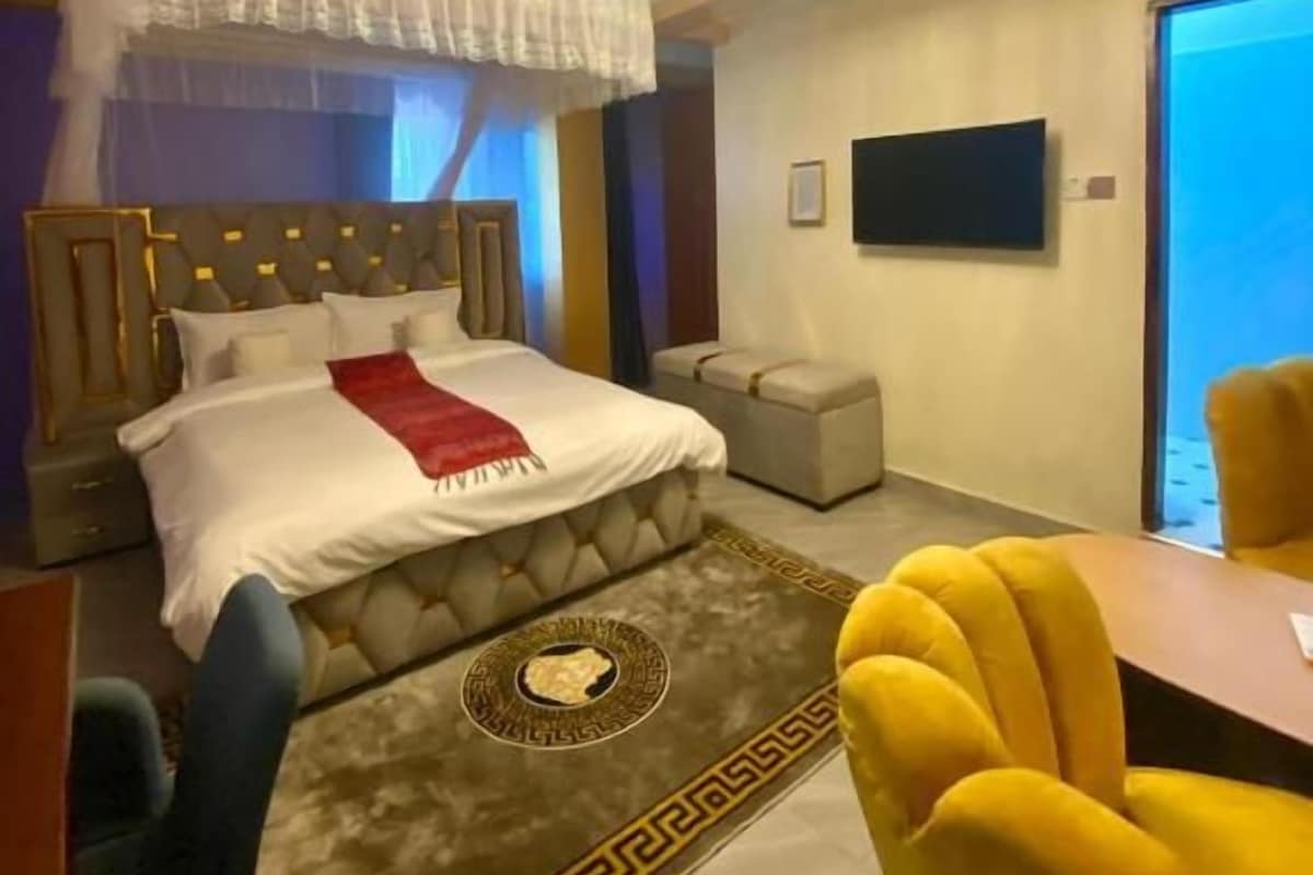 Una habitación de hotel con una cama, televisión, sofá y mesa de comedor.
