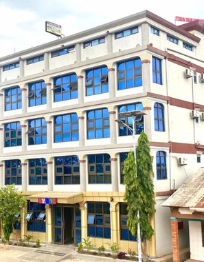 Un edificio de varios pisos con una entrada central, ventanas amplias y un cartel sobre la entrada.