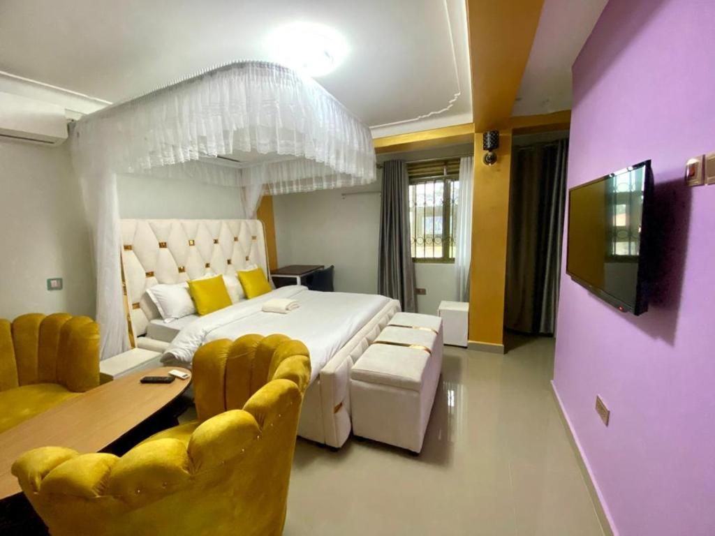 Une chambre d’hôtel avec un lit, une télévision, un bureau et des chaises jaunes.