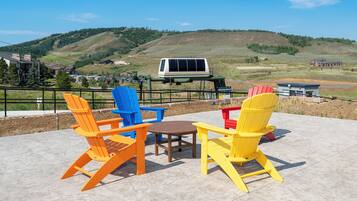 Outdoor seating with a view of a hilly landscape and a ski lift in the background.