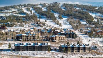 A ski resort with multiple buildings, including a large lodge and several smaller structures, surrounded by snow-covered terrain and trees.