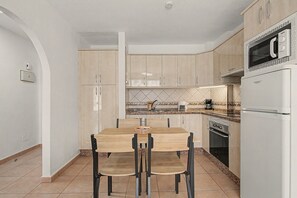 A modern kitchen with a dining table, chairs, a microwave, a coffee maker, and a stove. - Vacation Apartment 'Diamante Sol Los Cristianos' with Shared Pool and Wi-Fi (Los Cristianos)