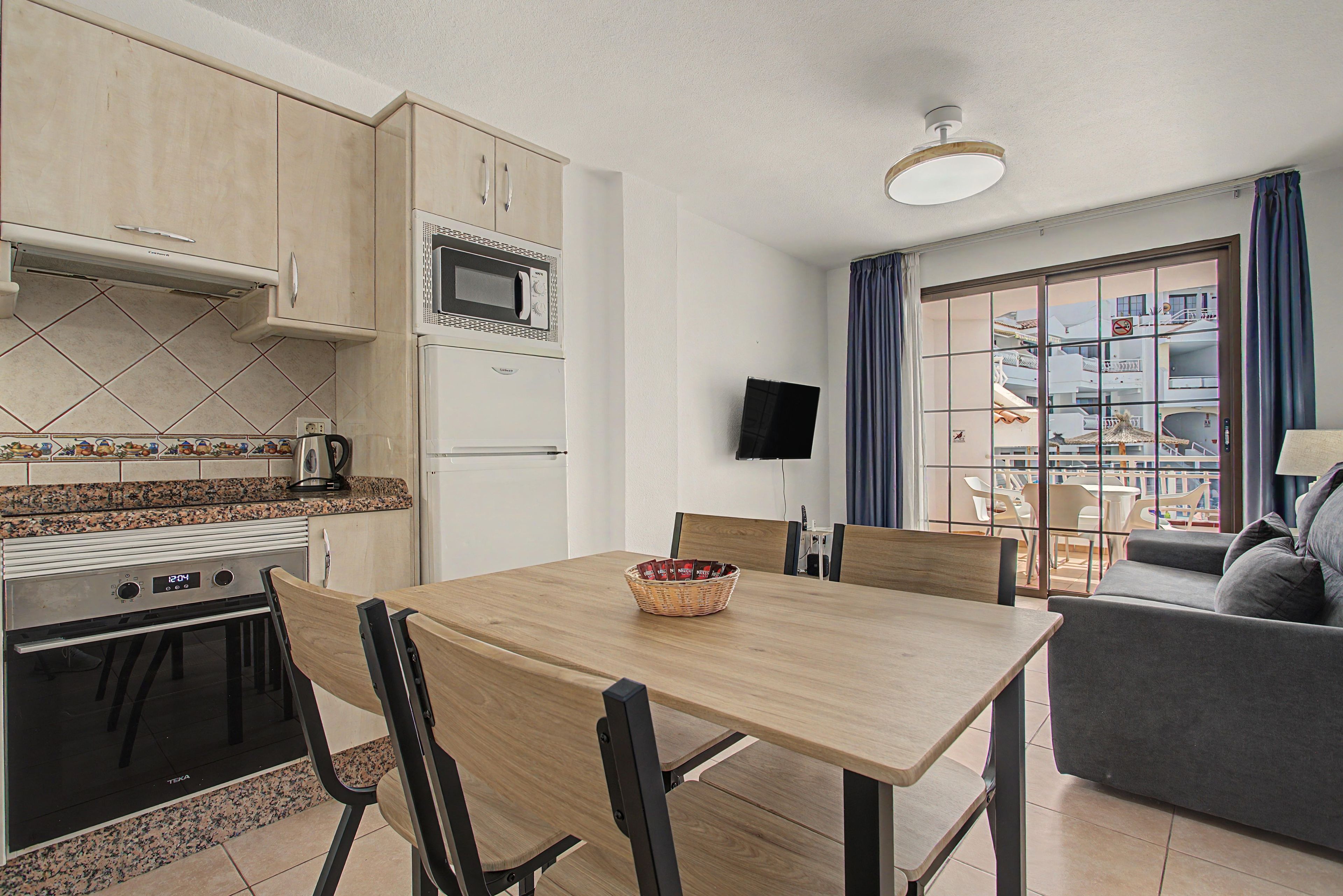 Un espace de vie compact comprenant un coin cuisine, un coin repas et un espace détente avec vue.