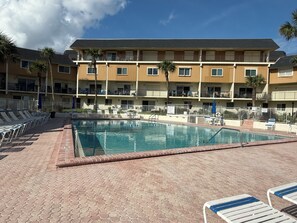 A hotel pool area with lounge chairs and a building with multiple balconies. - Lovely 2-bedroom ocean front penthouse in Ormond Beach (Ormond Beach)