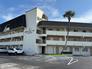A multi-story building with a sign reading 'Ormond Ocean Club A Condominium' and a parking lot with marked spaces. - Lovely 2-bedroom ocean front penthouse in Ormond Beach (Ormond Beach)