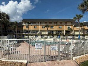 Ein Wohngebäude mit Poolanlage, einschließlich Liegestühlen und einem Schild mit Poolregeln.