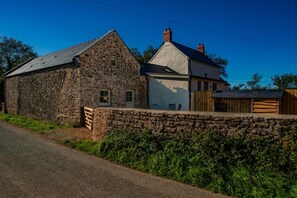 A stone building with a sloped roof, a wooden fence, and a clear sky. - Countryside Cottage - 2 En-Suites - Parking for 2 (Talbenny)