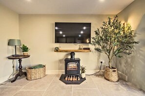 A living room with a fireplace, a television mounted on the wall, a lamp, and a potted plant. - Countryside Cottage - 2 En-Suites - Parking for 2 (Talbenny)