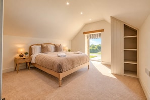 A bedroom with a large bed, a bedside table with a lamp, a window with a view, and a built-in closet. - Countryside Cottage - 2 En-Suites - Parking for 2 (Talbenny)