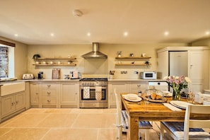 A kitchen with a central island, built-in oven, microwave, and stainless steel range hood. - Countryside Cottage - 2 En-Suites - Parking for 2 (Talbenny)